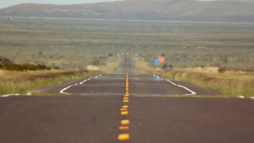 Long empty highway surrounded by flat grassy land
