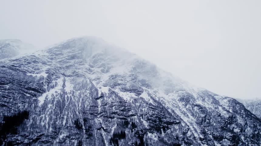 A huge snowcovered rock mountain in an environment that is cloudy