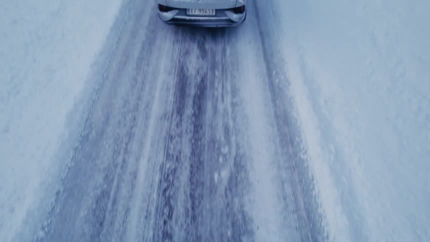An suv driving by a house in a rural area on a snowcovered road