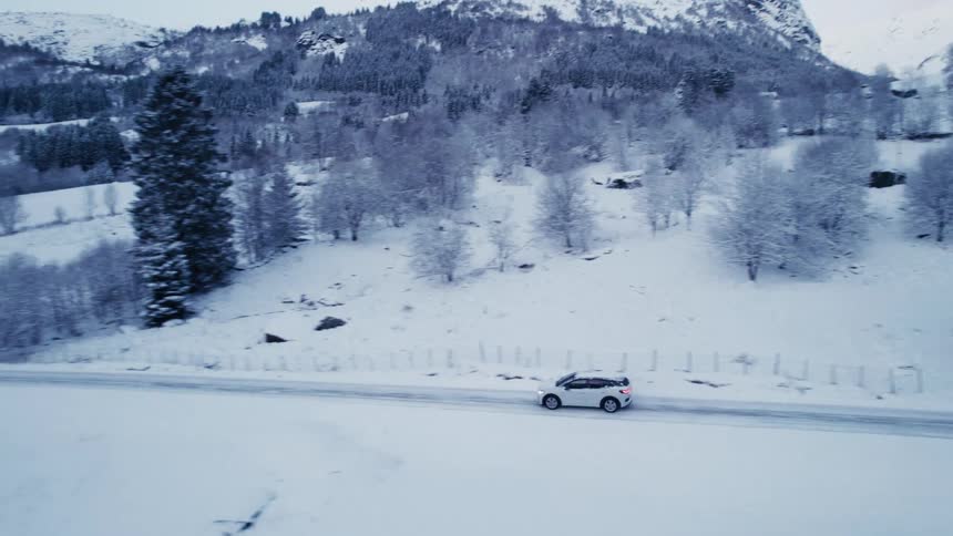 A car driving is a snowcovered road near a town with wooden houses