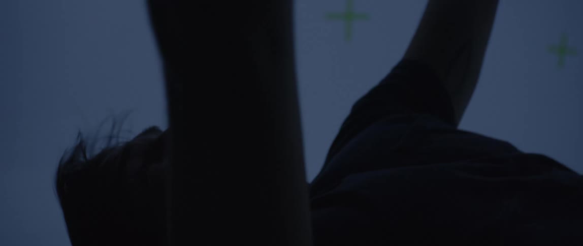 Close up of a man with hair flowing hands raised as if plummeting from great heights but he is actually in a dimly lit motion capture studio