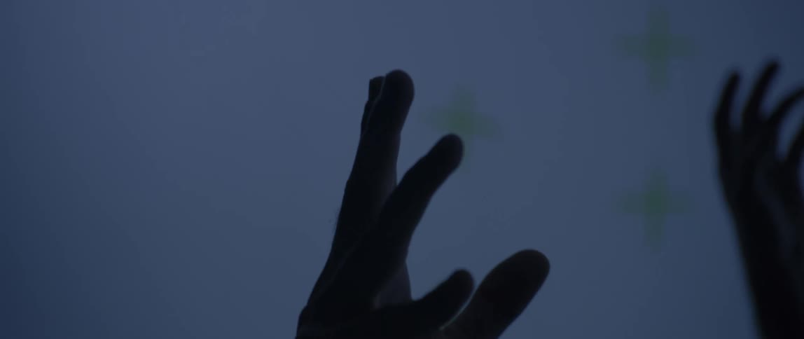 Close up of hands raised in a dimly lit motion capture studio