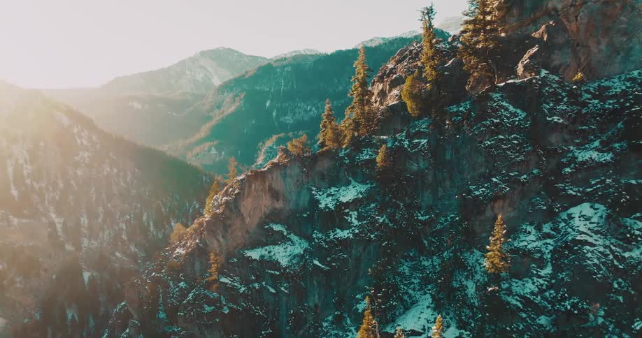 Aerial view of a forested mountain canyon bathed in golden sunrise or sunset light