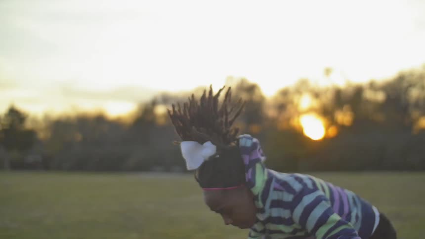 A woman does a flip on a field at dawn