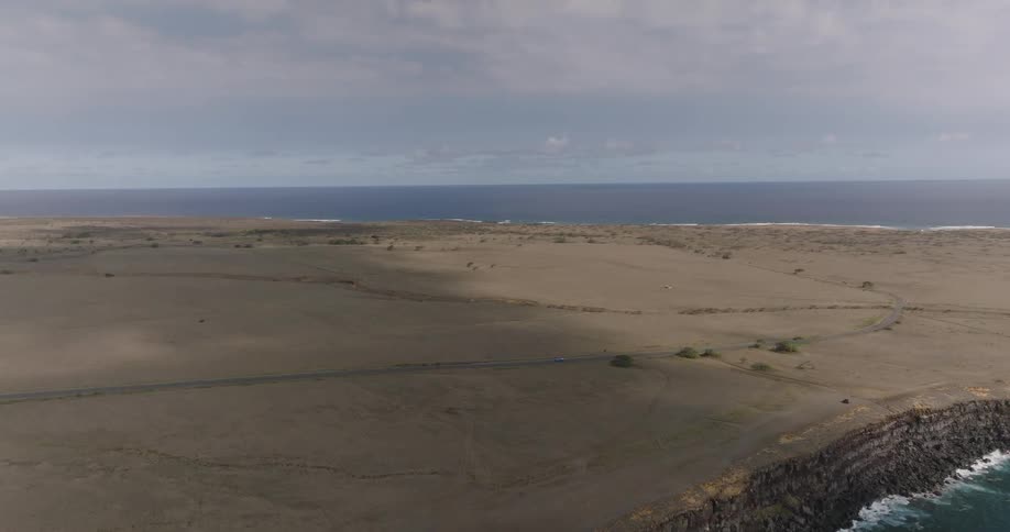 A coastal island at midday has a surface covered with grassy plains
