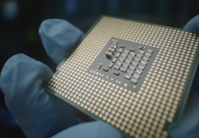A person wearing blue gloves is holding a computer cpu chip