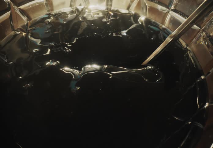 Closeup of a spoon plunging into a dimly lit bowl of dark jello