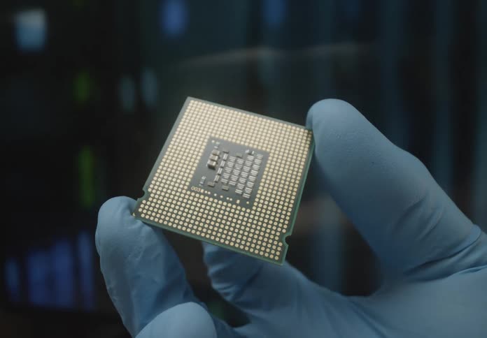 A person wearing blue gloves is holding a computer cpu chip