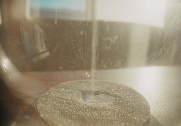 A closeup shows fine powder swirling in a controlled stream under warm light