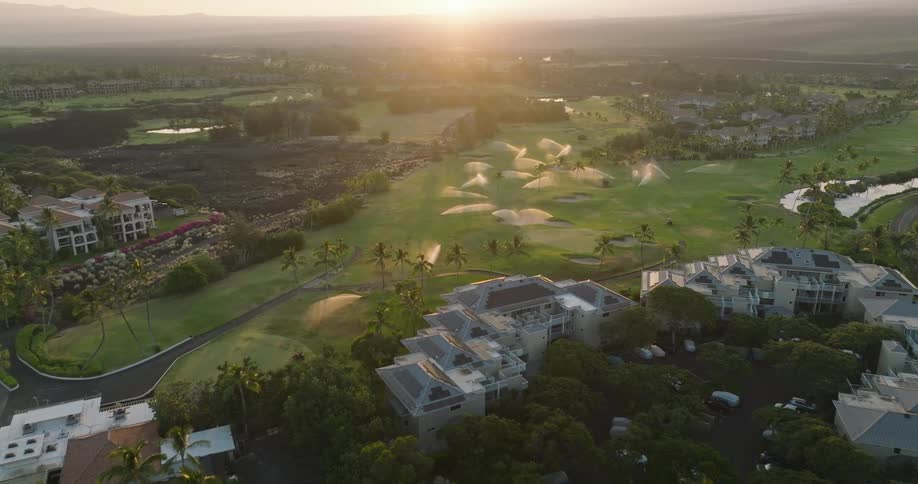Aerial view of tropical golf course and resort at sunrise with sprinklers on