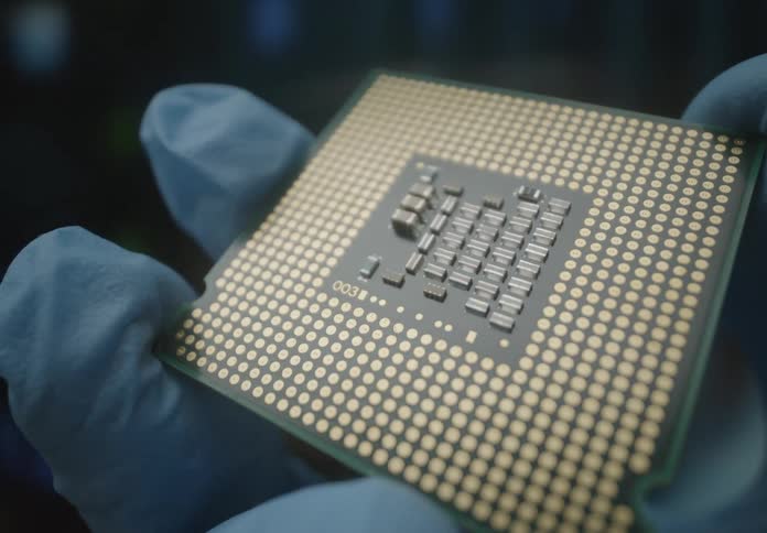 A gloved hand spins a cpu revealing its gold pin grid
