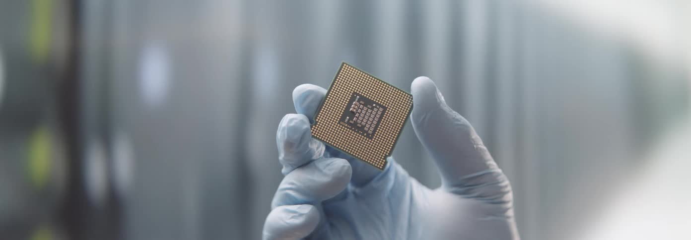 Person holds a computer chip in a gloved hand