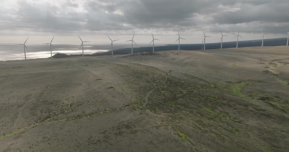 Aerial shot of wind power platforms in mountains with a river in the background