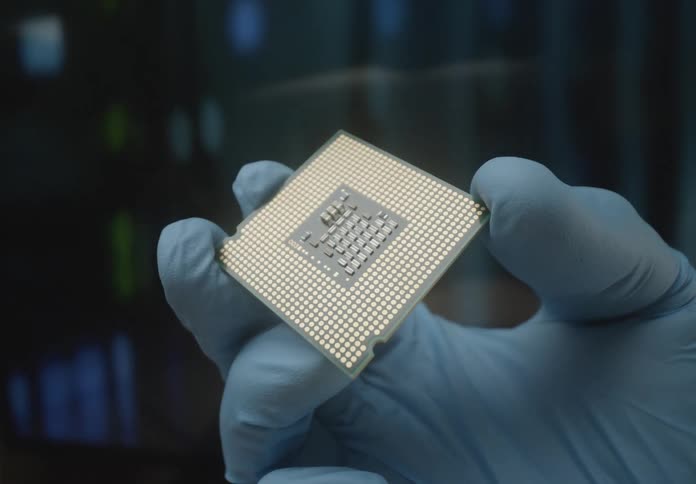 A persons hand wearing a blue glove is holding and inspecting a computer cpu