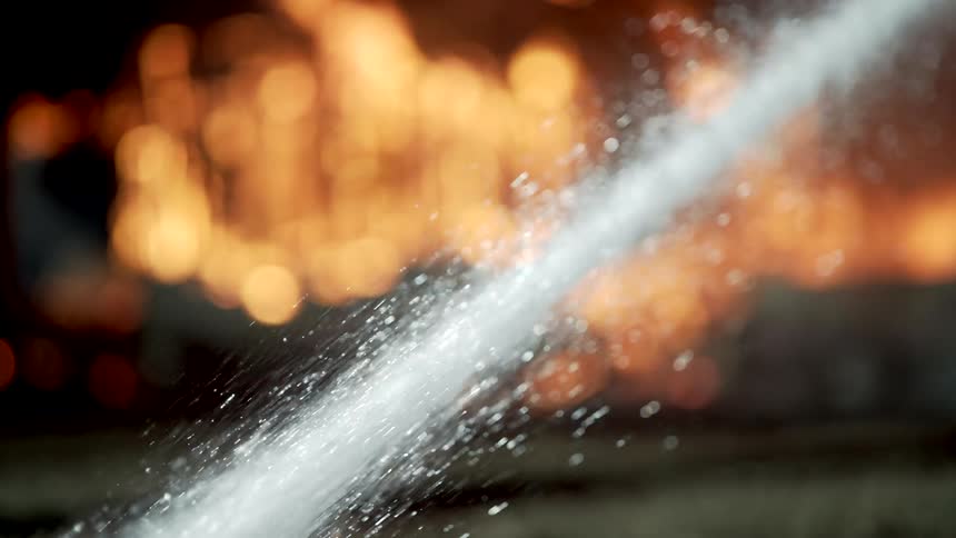 Soaker hose close up hosing down fire in the distance