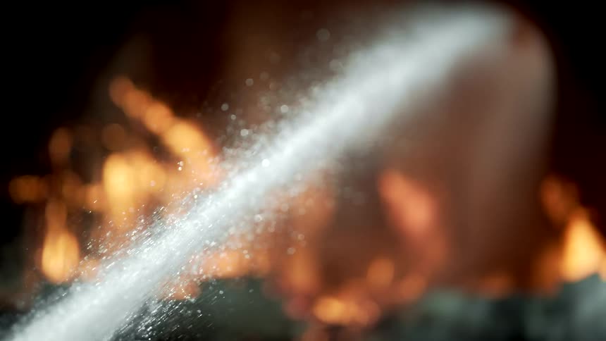 A stream of water is shooting towards the burning home