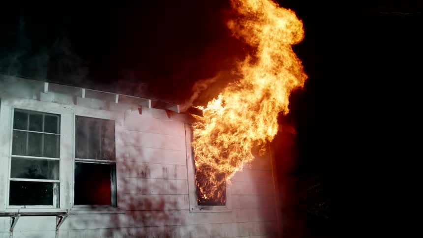 Fire is shooting from the window on the burning home