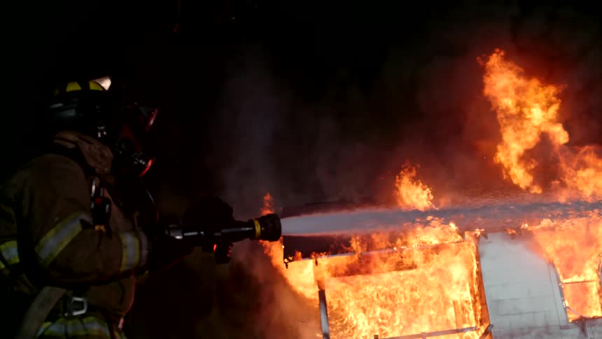 A firefighter is spraying water on a burning home