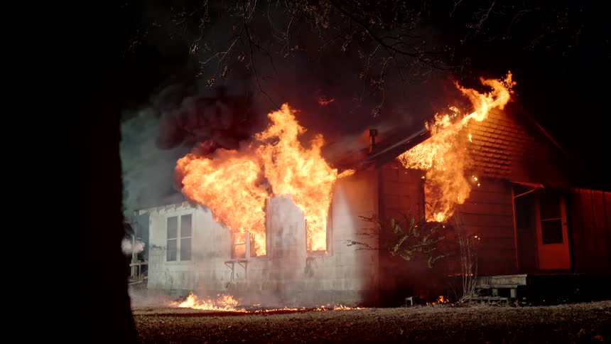 Water is being sprayed on the burning home at night