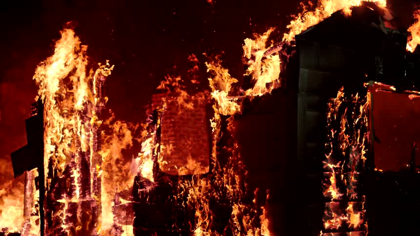 Structure of a building engulfed in flames in slow motion at night