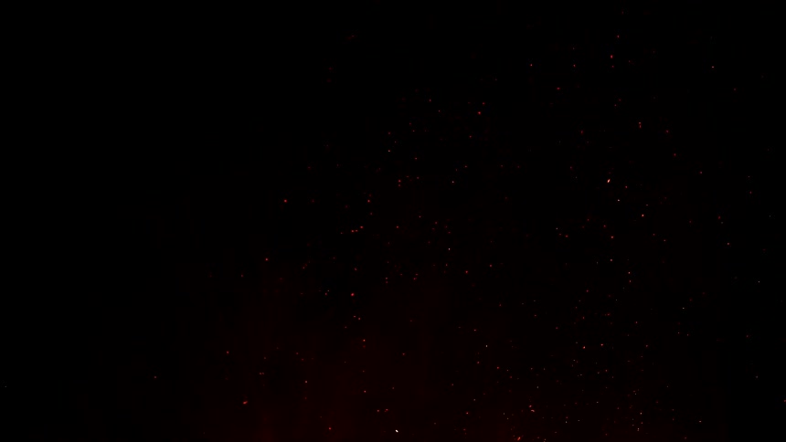 Flames and ember rising in the night sky in slow motion