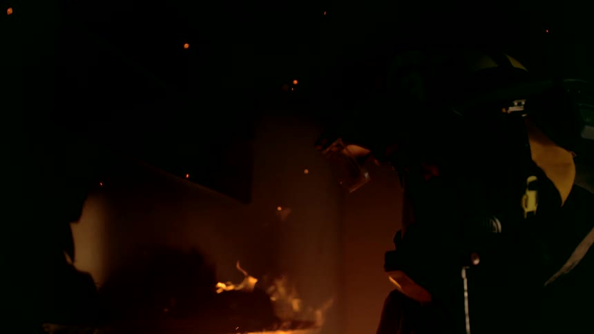 Firefighters move through the dark burning home