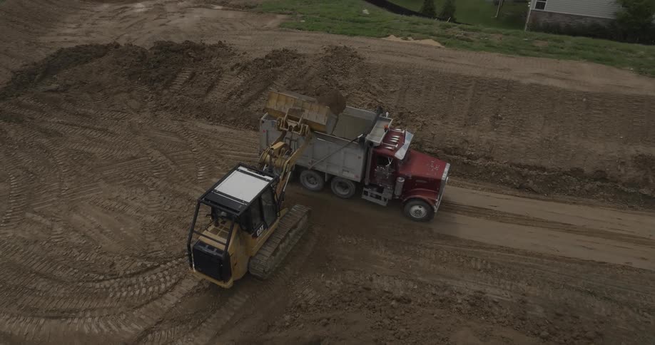 A bulldozer and a dump truck are working on a dirt construction site
