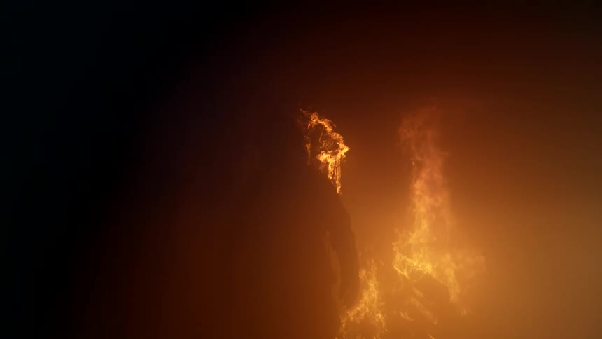 Silhouette of a person walking out of a burning fire at night