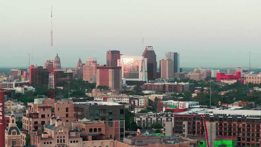 An aerial view of san antonio texas reveals a cityscape featuring a blend of lowrise and highrise buildings beneath a hazy sky