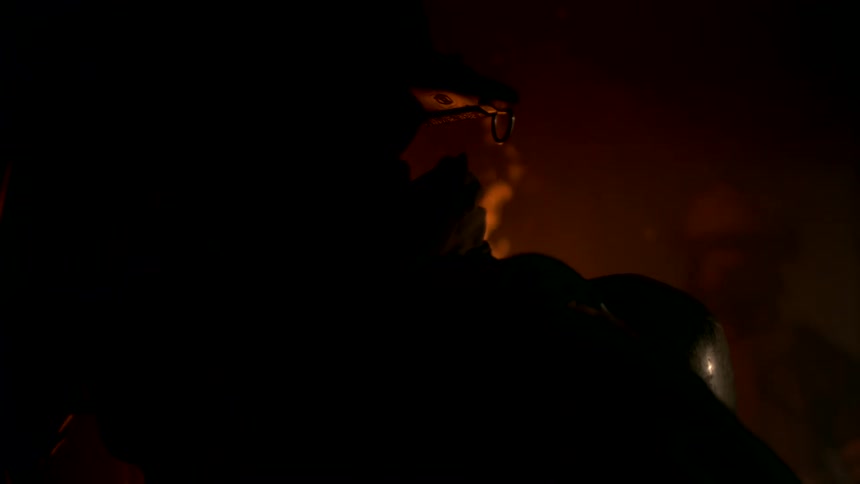The silhouette of two firefighters standing in an interior that is on fire with a bright orange flame