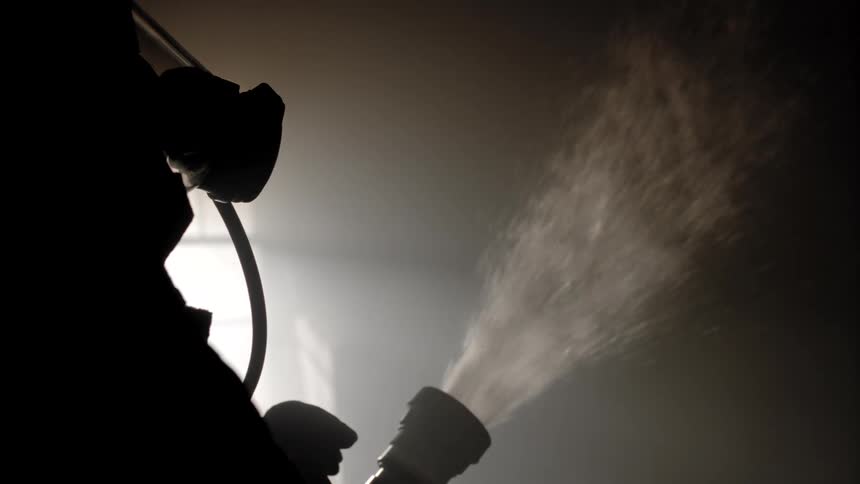 A firefighter in full gear adjusts the water coming from a hose