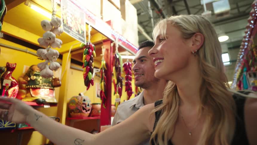 A man and a woman inside a market smiling as they check out a product from a store