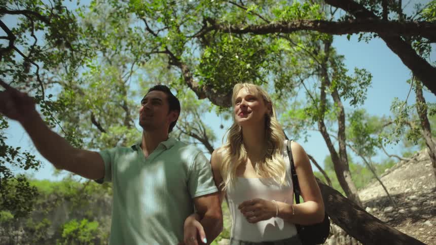 Man and woman walking in a forest area holding hands at daytime