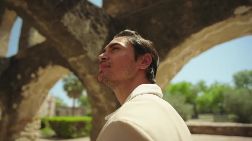 The face of a young man who is walking through an old concrete structure and observing it