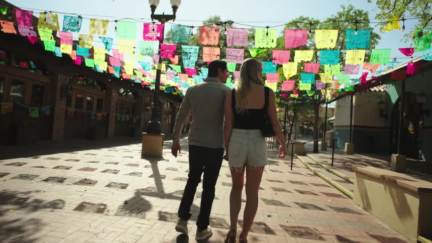 Couple walks hand in hand under pennant banners lining a street