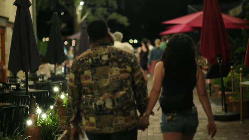 A man and woman skip through town at night