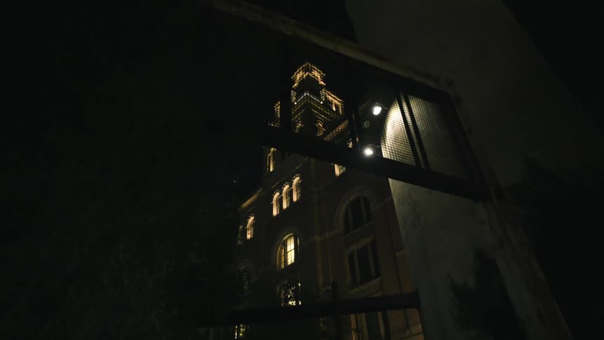 A large building with lights on at night and with large windows