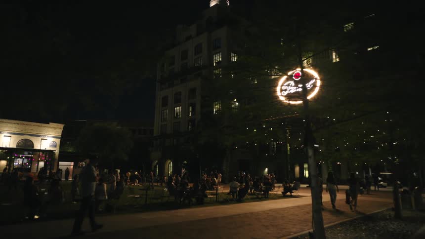 People are sitting outside and walking around the city