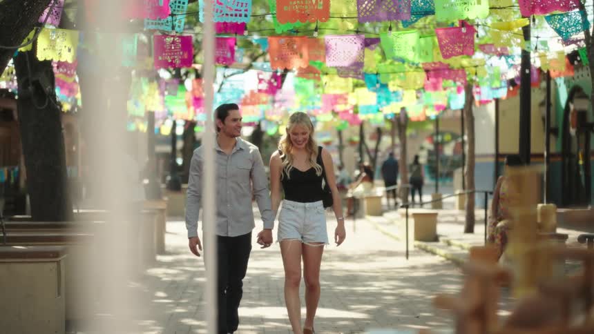 A man and woman walk handinhand down a street in a city