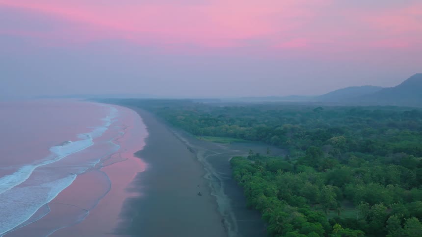 Aerial of ocean waves rolling into a beach at sunset