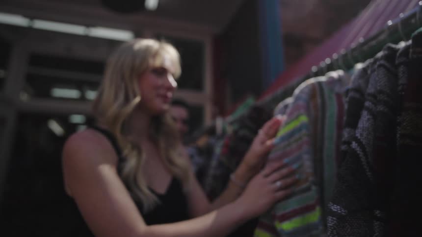 A woman is looking through clothes that are hanging on a rack
