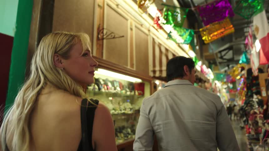 Couple walks through a covered market decorated with colorful bunting and craft shops