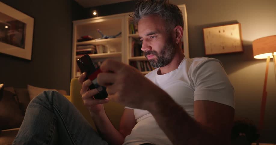 Man sitting on couch making a purchase with his credit card on his cell phone