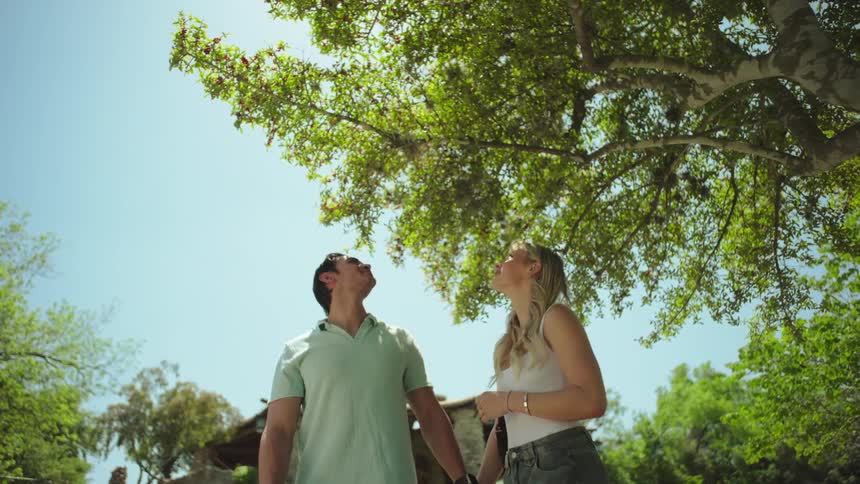 A couple hold hands while hiking past trees