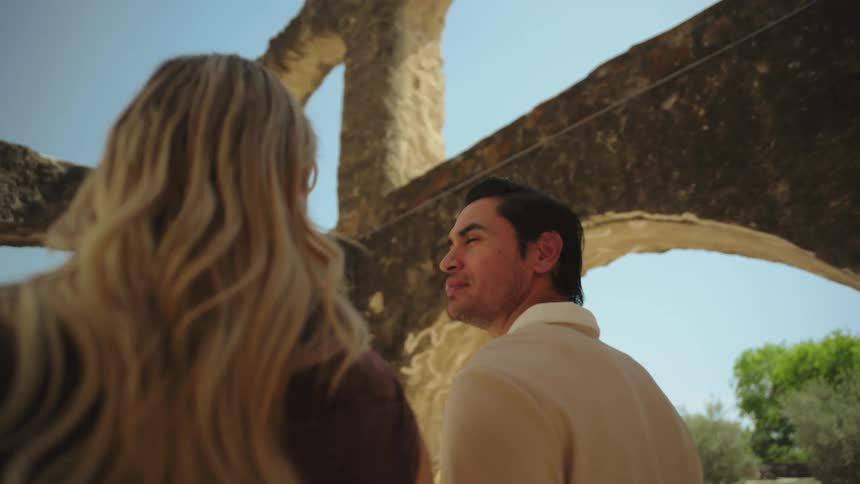 Couple looks at stone ruins under blue sky on a sunny day