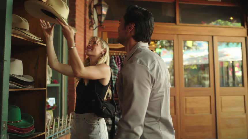 A woman puts a cowboy hat on a mans head