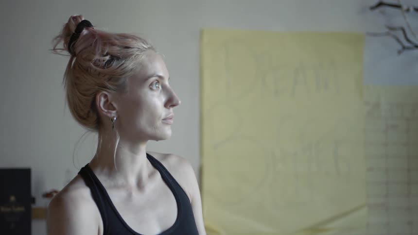 A woman with a messy bun stands indoors
