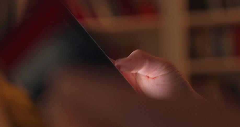 An adults hand scrolls on a smartphone indoors