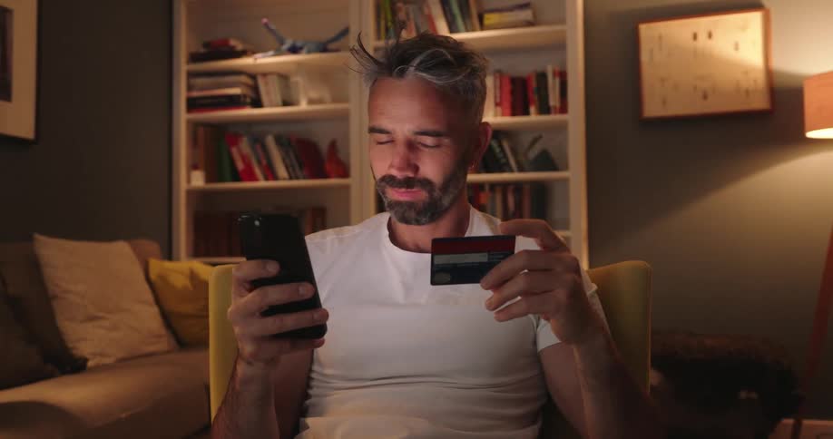 The man is typing his credit card into his cell phone