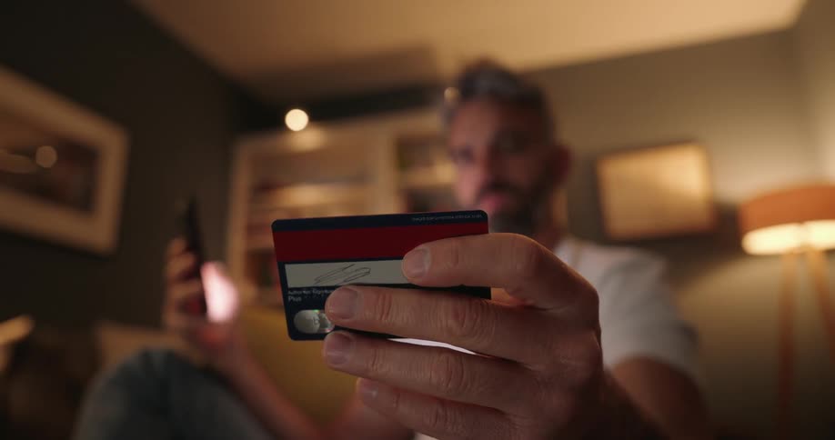 A man is inputting his credit card into a cell phone